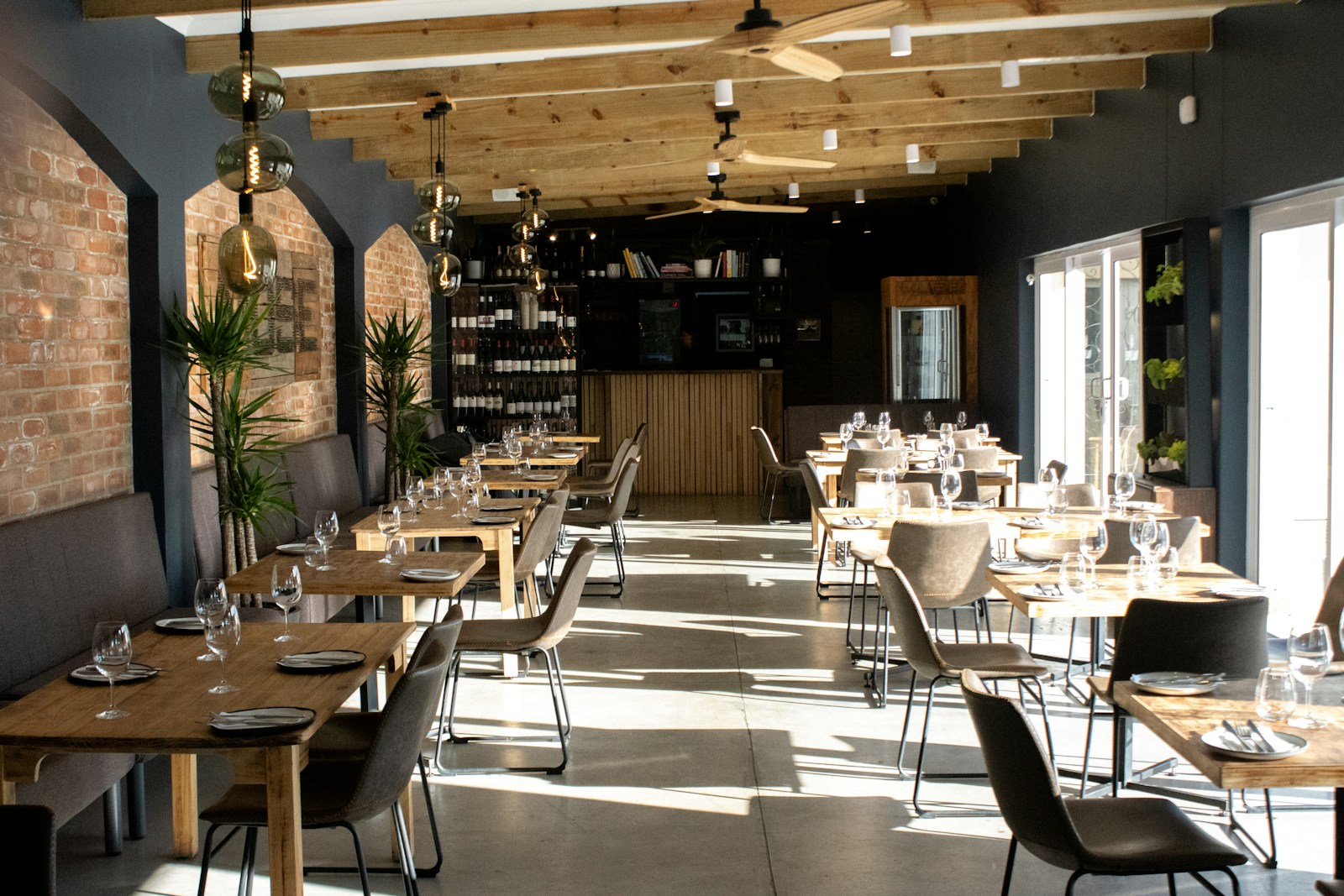 Jasne wnętrze restauracji z drewnianymi stolikami przygotowanymi dla gości